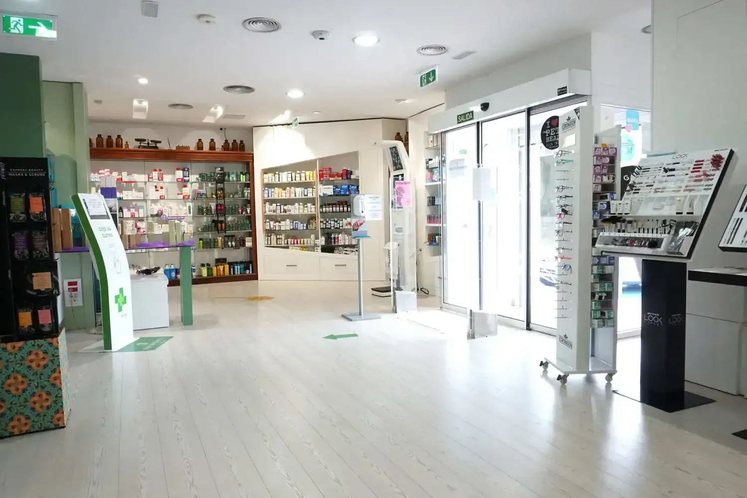 El interior de una farmacia con muchos estantes y una puerta corrediza de vidrio.