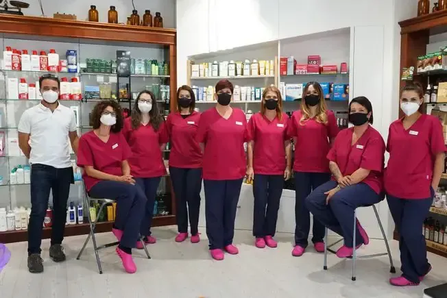 Un grupo de personas con máscaras posan para una fotografía en una farmacia.