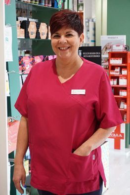 Una mujer con una blusa rosa sonríe en una farmacia.