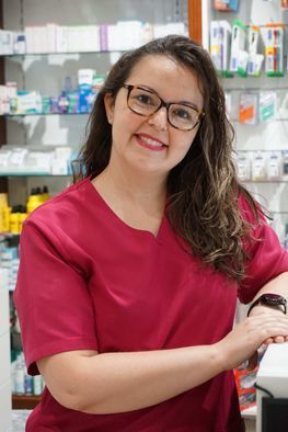 Una mujer que lleva gafas y una blusa roja está parada en una farmacia.