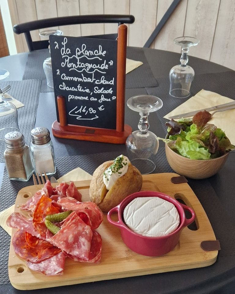 Table avec une planche de fromages, de la charcuterie et une petite salade