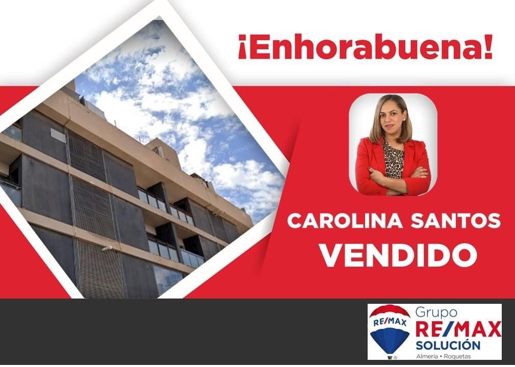 Una mujer con una chaqueta roja está parada frente a un edificio.