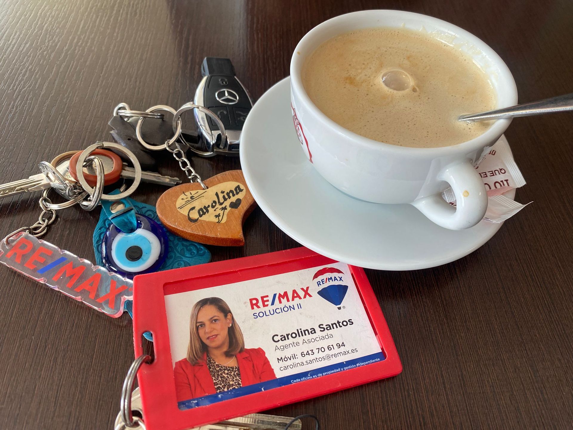 Una taza de café en un platillo junto a una tarjeta remax