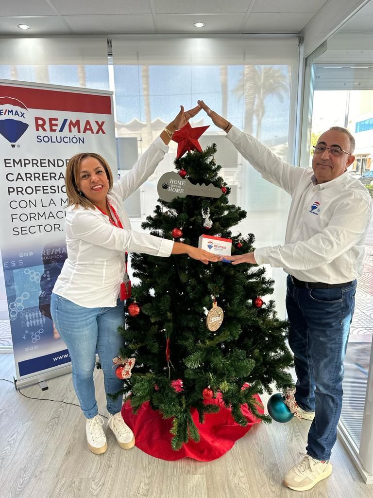 Un hombre y una mujer están de pie junto a un árbol de Navidad.
