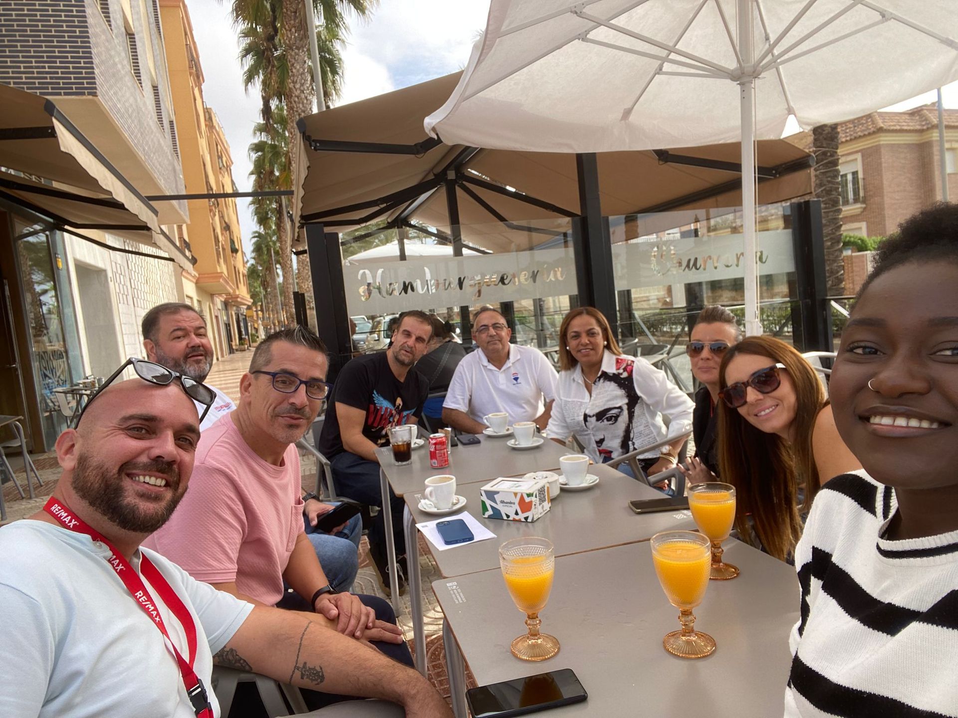 Un grupo de personas está sentada en una mesa con vasos de jugo de naranja.