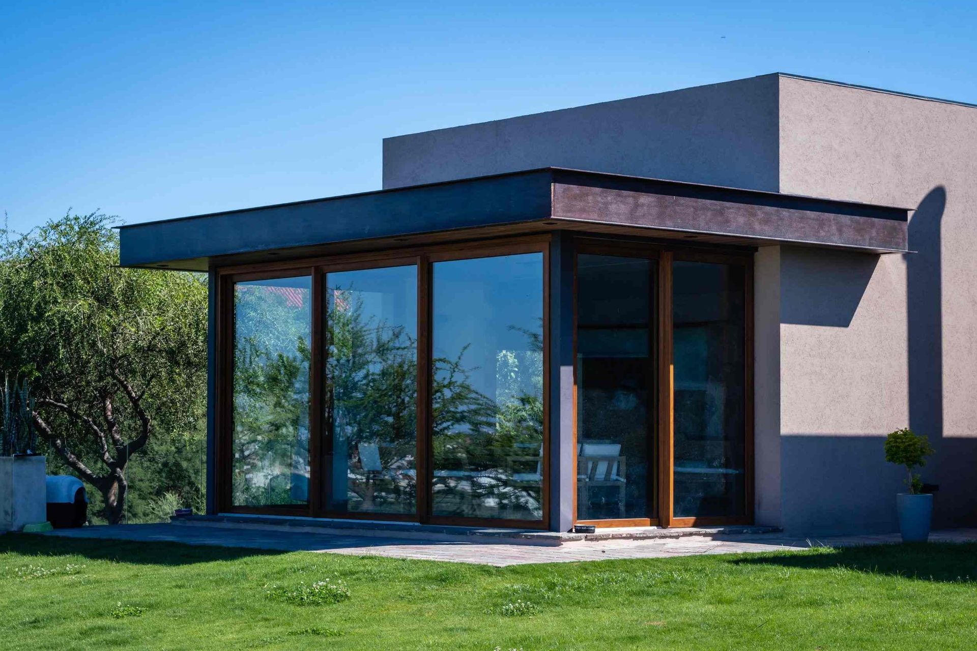 Una casa con muchas ventanas está situada encima de un exuberante campo verde.
