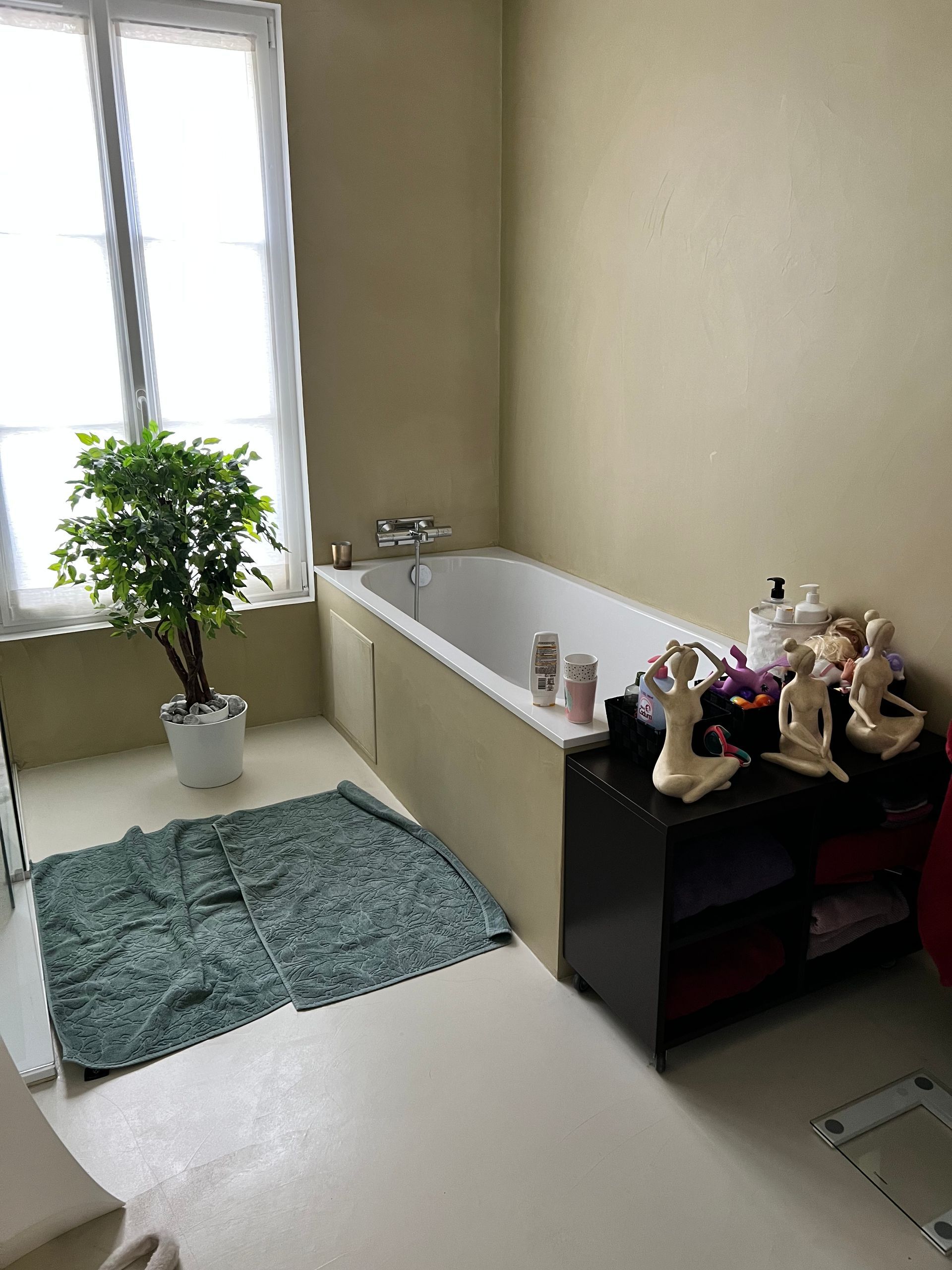 Salle de bains beige avec une baignoire et une plante