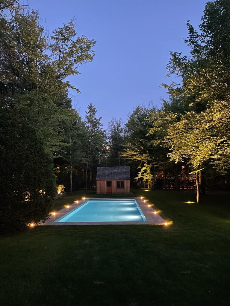 Une piscine rectangulaire de nuit, éclairée sur les côtés