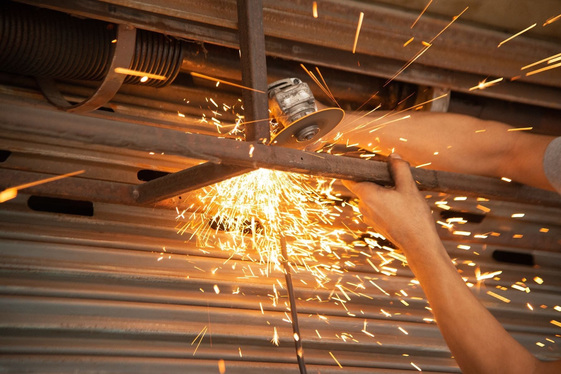 Una persona está cortando un trozo de metal con una amoladora.