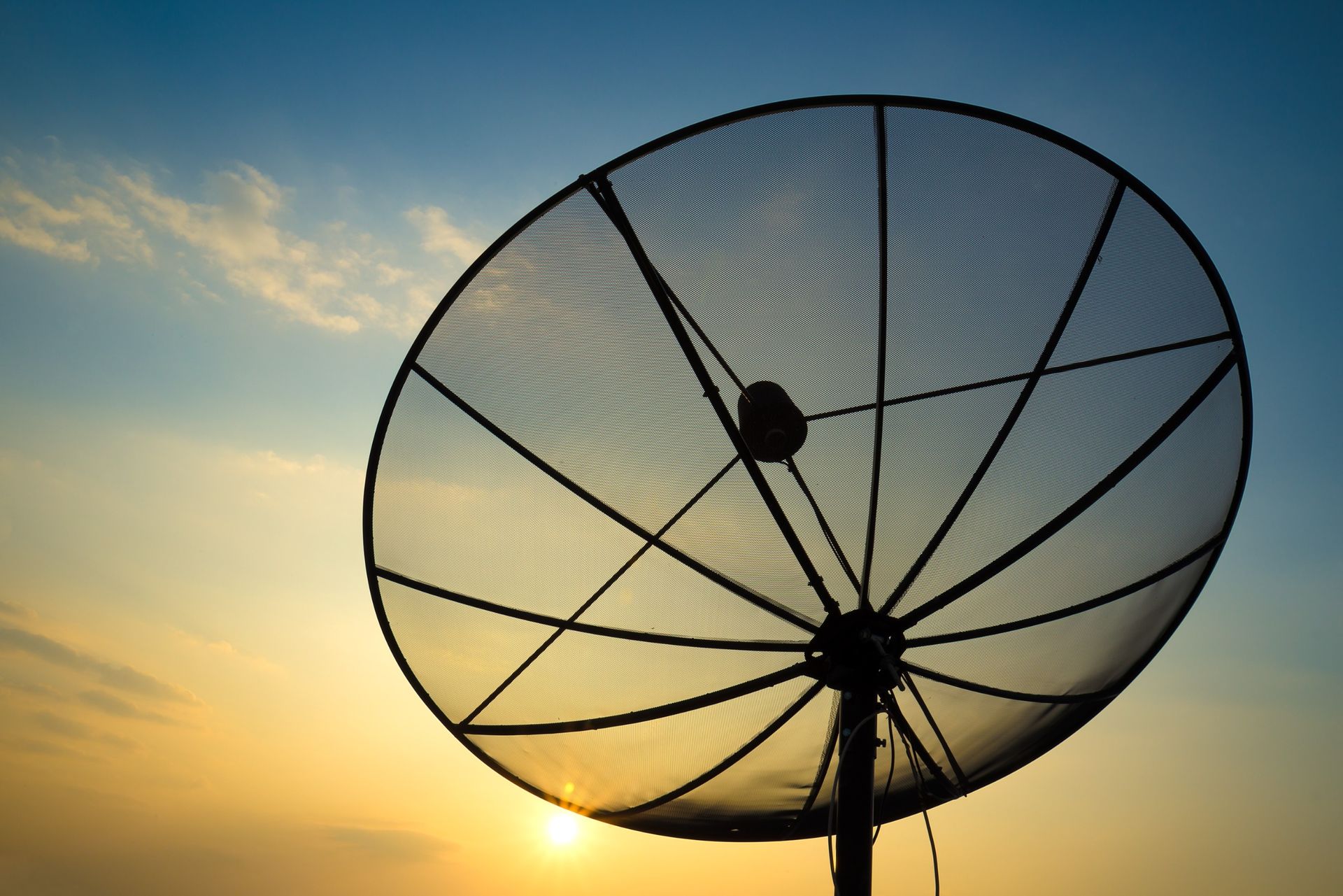 Una antena parabólica se recorta contra el cielo del atardecer.