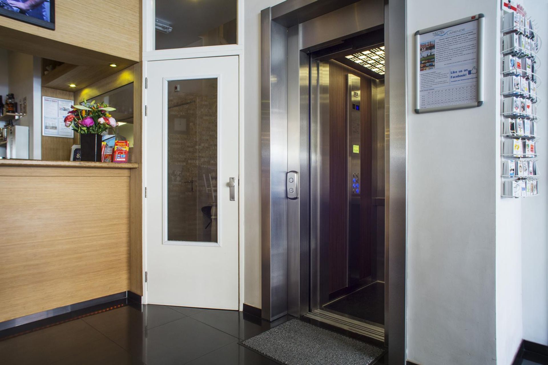 Lobby with a stainless steel elevator, white door, and reception counter on the left