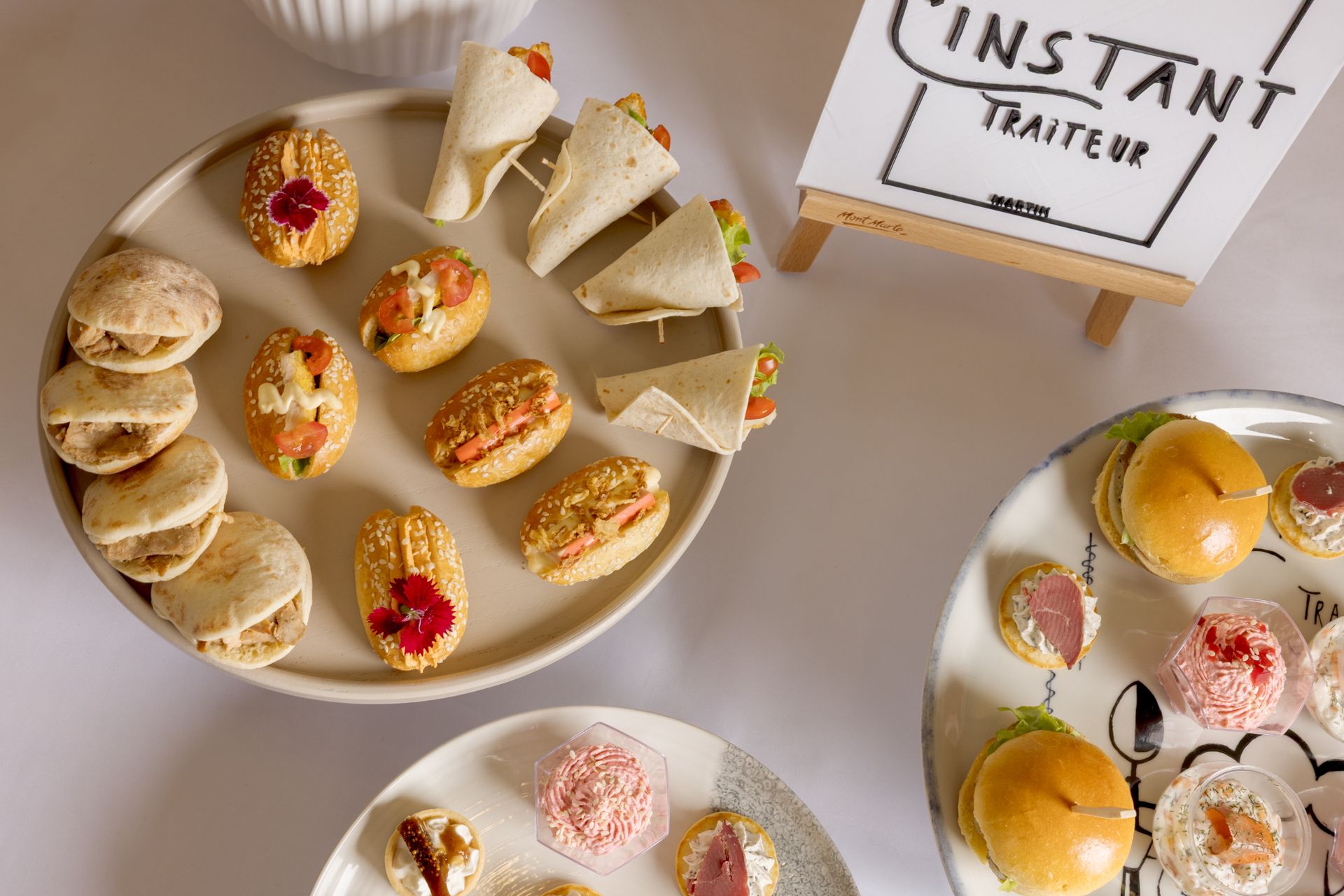 Plateau de pâtisseries assorties en format mini sur des assiettes à côté d'un panneau « Instant Trailer ».