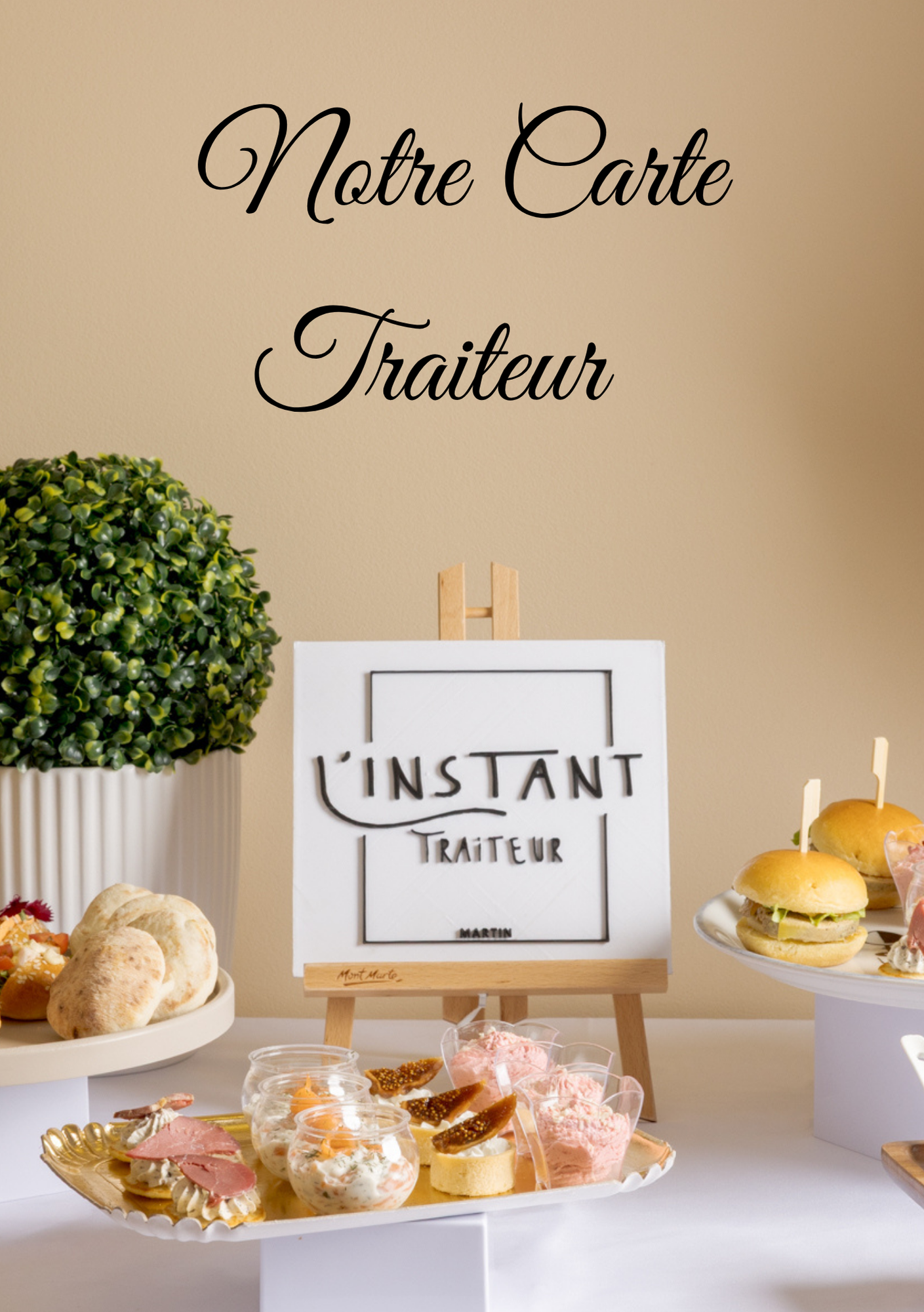 Présentoir de buffet traiteur avec pâtisseries, sandwichs et une pancarte indiquant « L'Instant Traiteur » sur fond beige