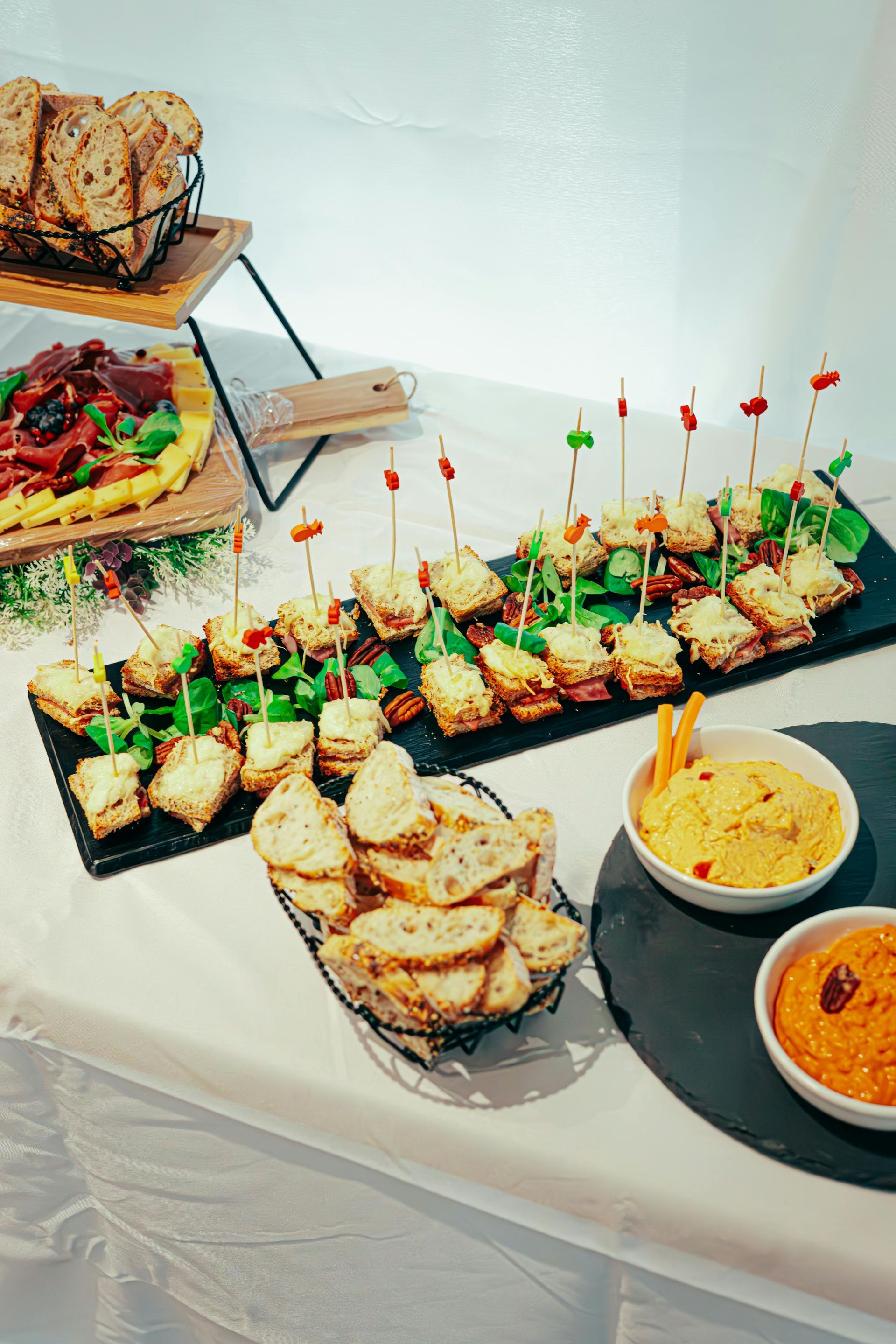 Buffet de fête avec amuse-gueules, pain, sauces et brochettes présentés sur des plateaux et des plats.