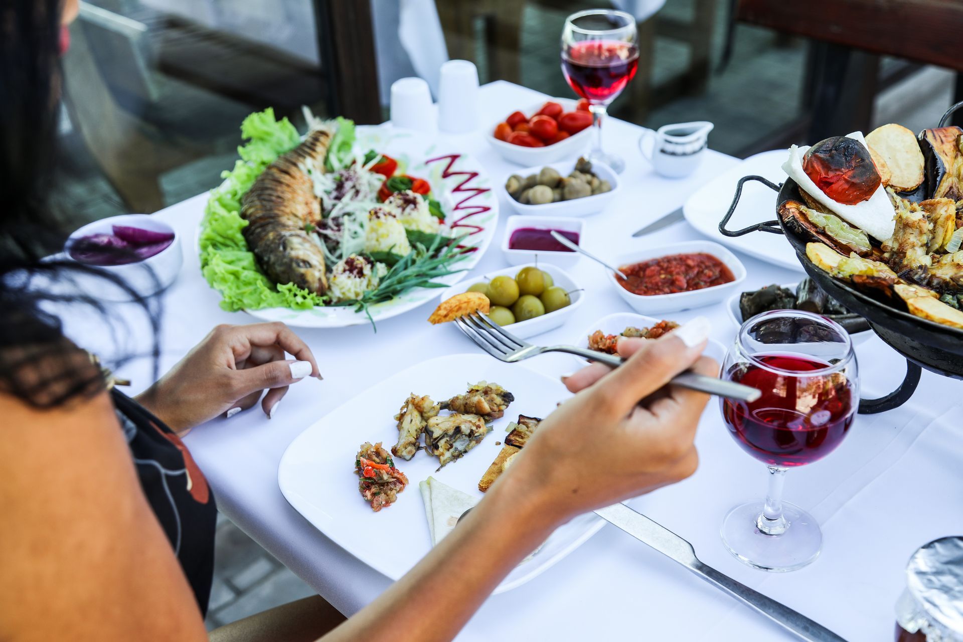 Serveur servant des amuse-gueules à l'assiette, accompagnés de salades, d'olives et de verres à vin, dans un restaurant.