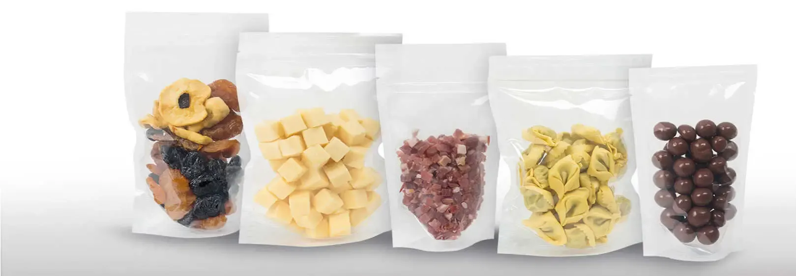 Fünf durchsichtige Snacktüten mit verschiedenen Leckereien.