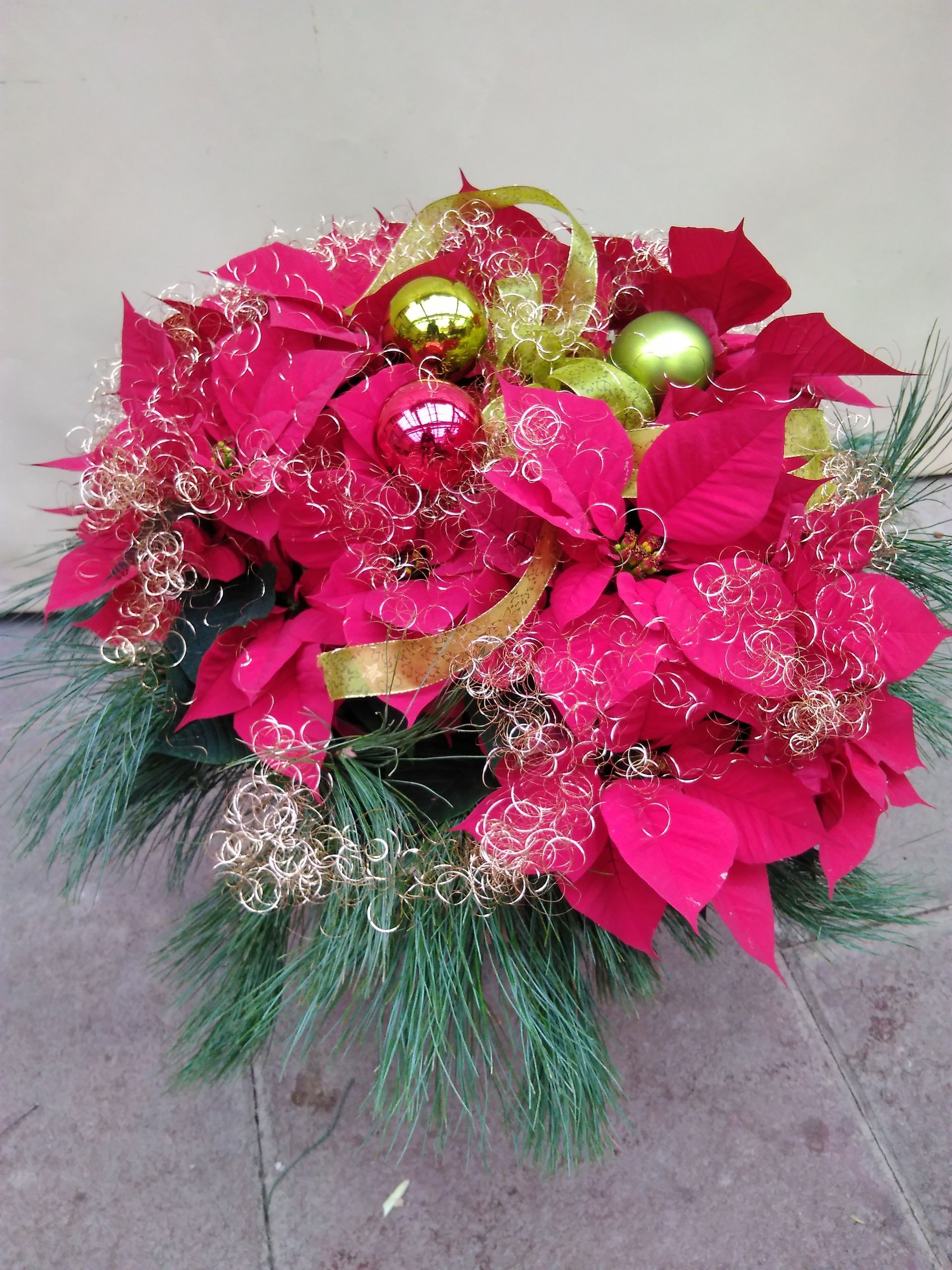 Weihnachtsstern-Tafelaufsatz mit roten Blumen, grünen und roten Ornamenten und goldenen Akzenten.