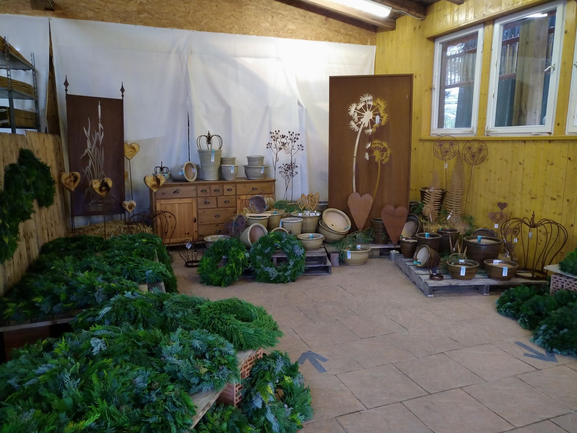 Eine Ausstellung von Kränzen, Keramik und dekorativer Kunst in rustikalem Werkstattambiente.