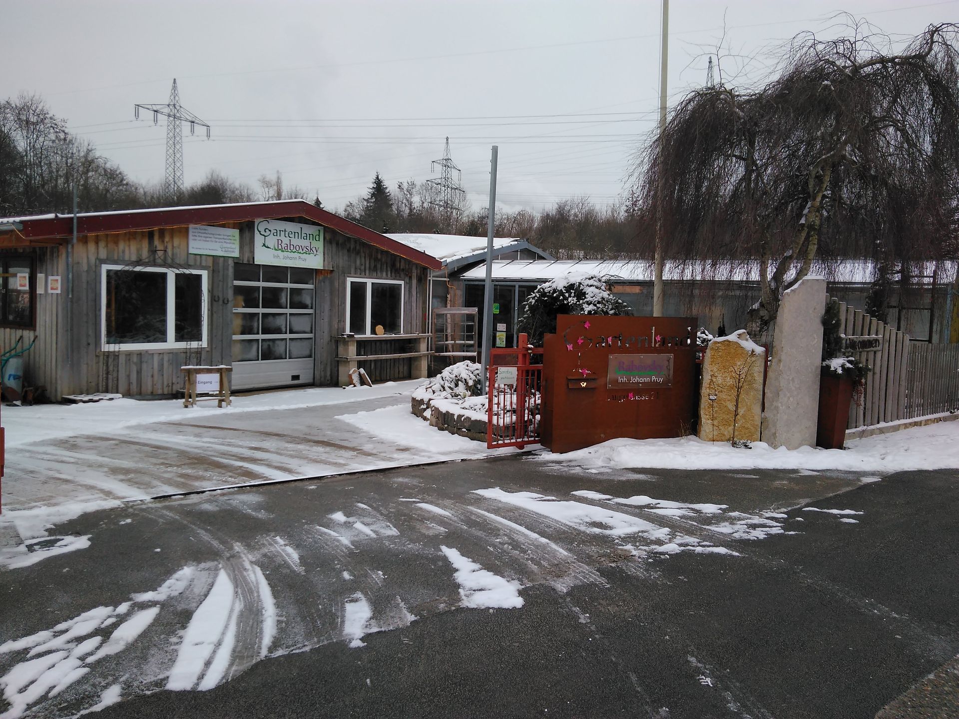 Die schneebedeckte Außenseite eines verwitterten Holzgebäudes mit mehreren Fenstern und einer Auffahrt.