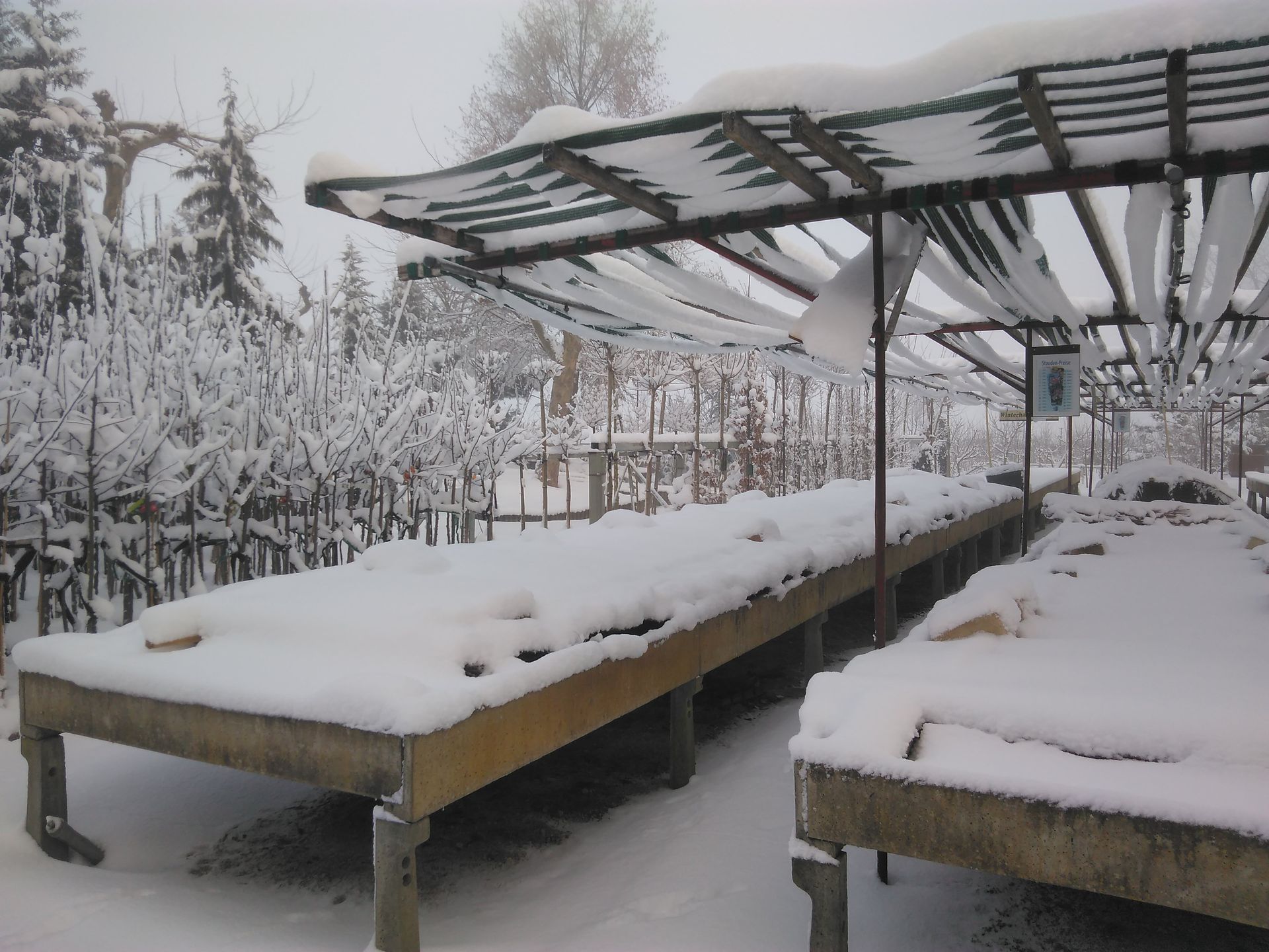 Schneebedeckte Markttische und Markisen in winterlicher Umgebung.