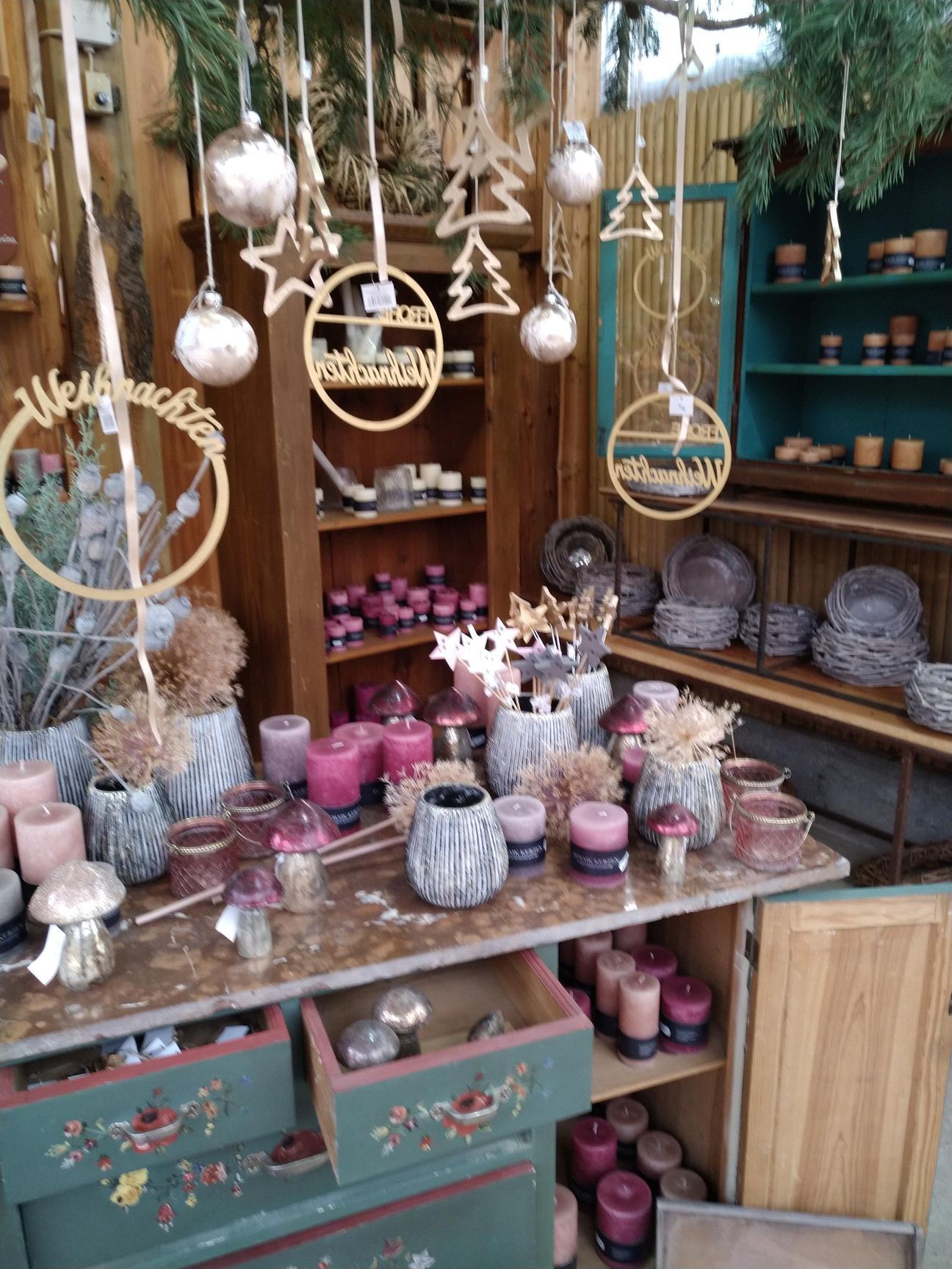 Schaufenster mit Weihnachtsdekoration, Kerzen, Ornamenten und Holzakzenten.