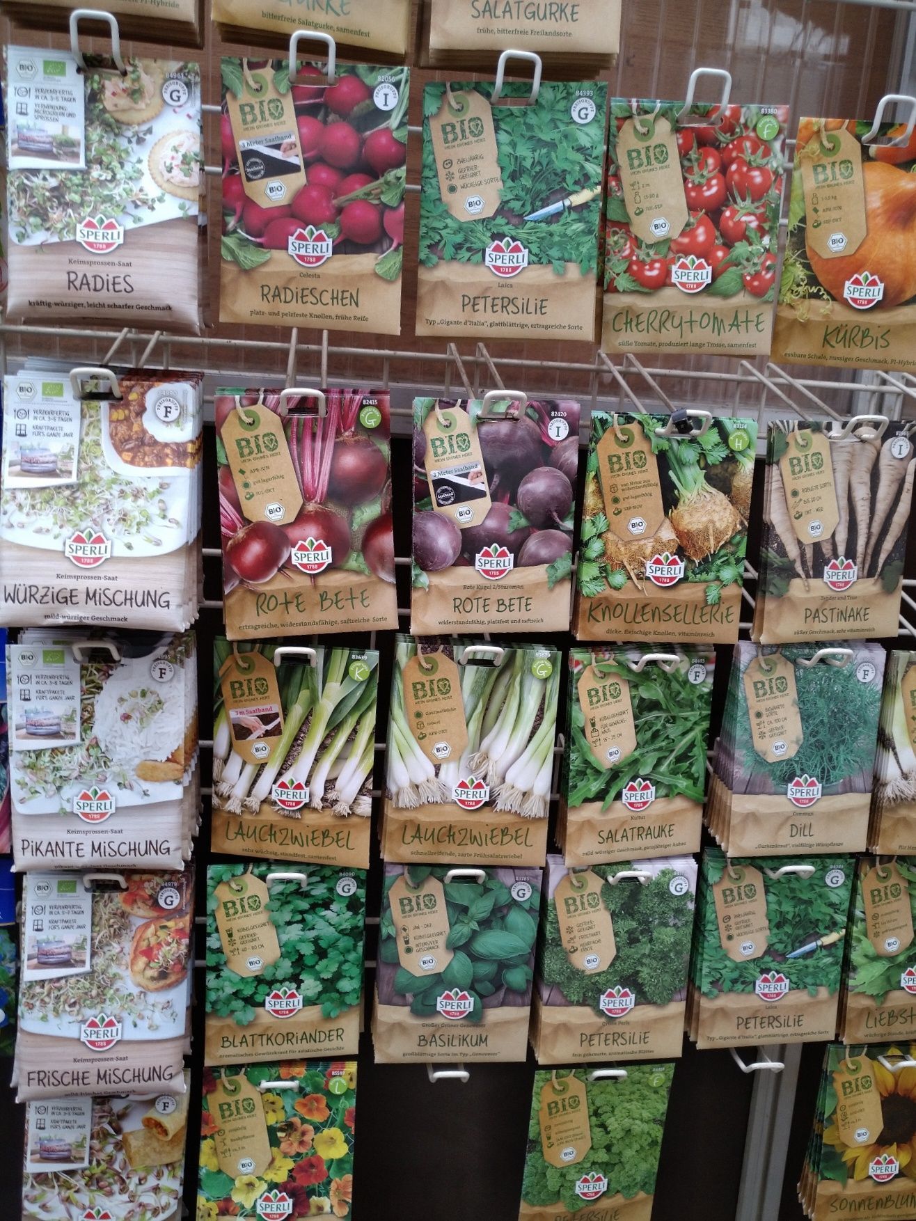Samenpakete verschiedener Gemüsesorten werden in einem Ladenregal ausgestellt.