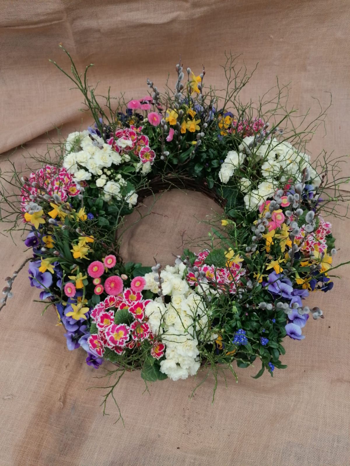 Blumenkranz in verschiedenen Farben auf Sackleinen-Hintergrund.