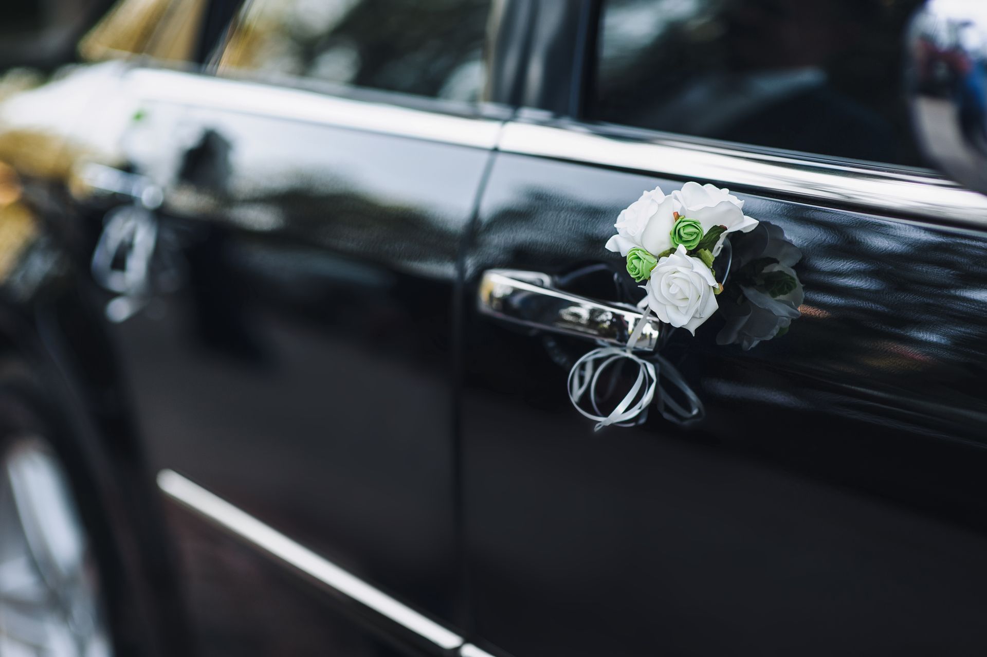 Eine Nahaufnahme eines Hochzeitsautos mit Blumen am Türgriff