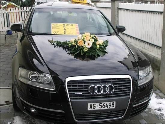 Ein schwarzer Taxi mit Blumen auf der Motorhaube. Foto von der Taxi von Burg Bryner GmbH