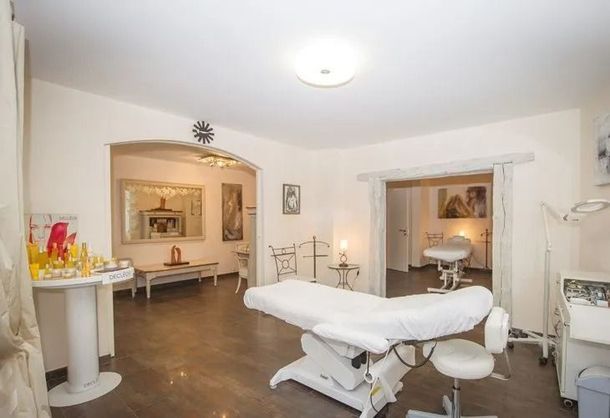 Salle de soins lumineuse avec table de massage, éclairage chaleureux et miroirs ornés.