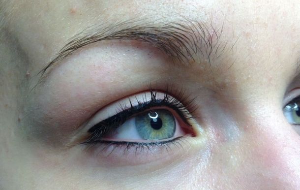 Gros plan sur des yeux bleus aux longs cils et aux sourcils soigneusement épilés.