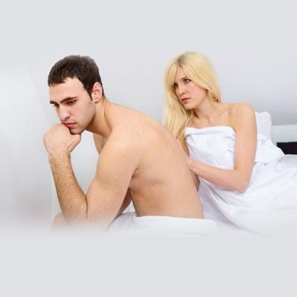 Un hombre y una mujer están sentados espalda con espalda en una cama.