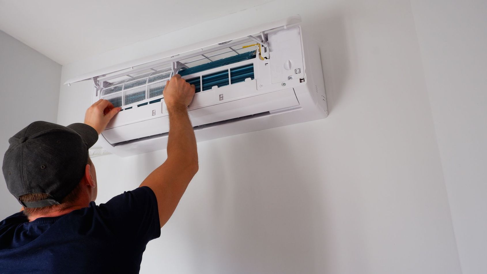 Un technicien nettoie l'intérieur d'un climatiseur mural.