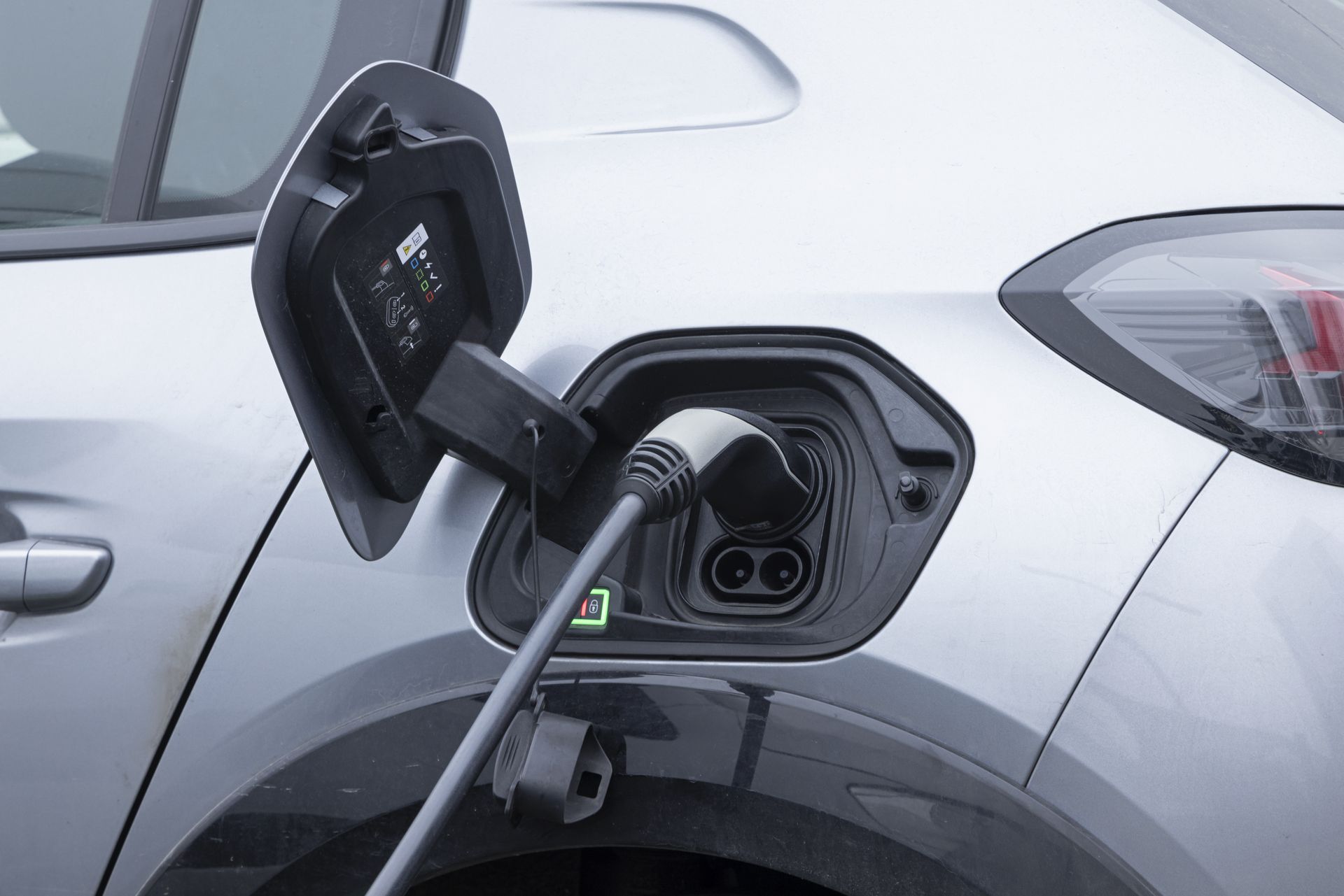 Voiture électrique argentée en charge à une station.