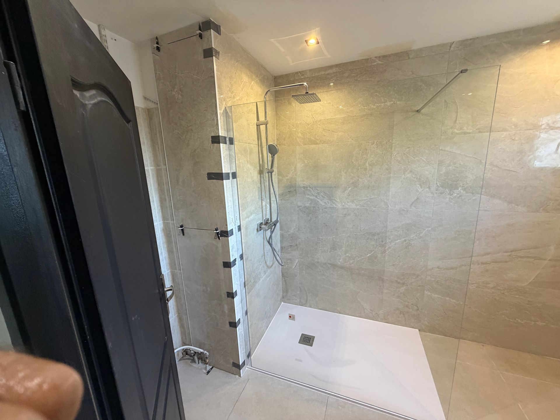 Salle de bains moderne avec paroi de douche en verre, murs carrelés et receveur de douche.
