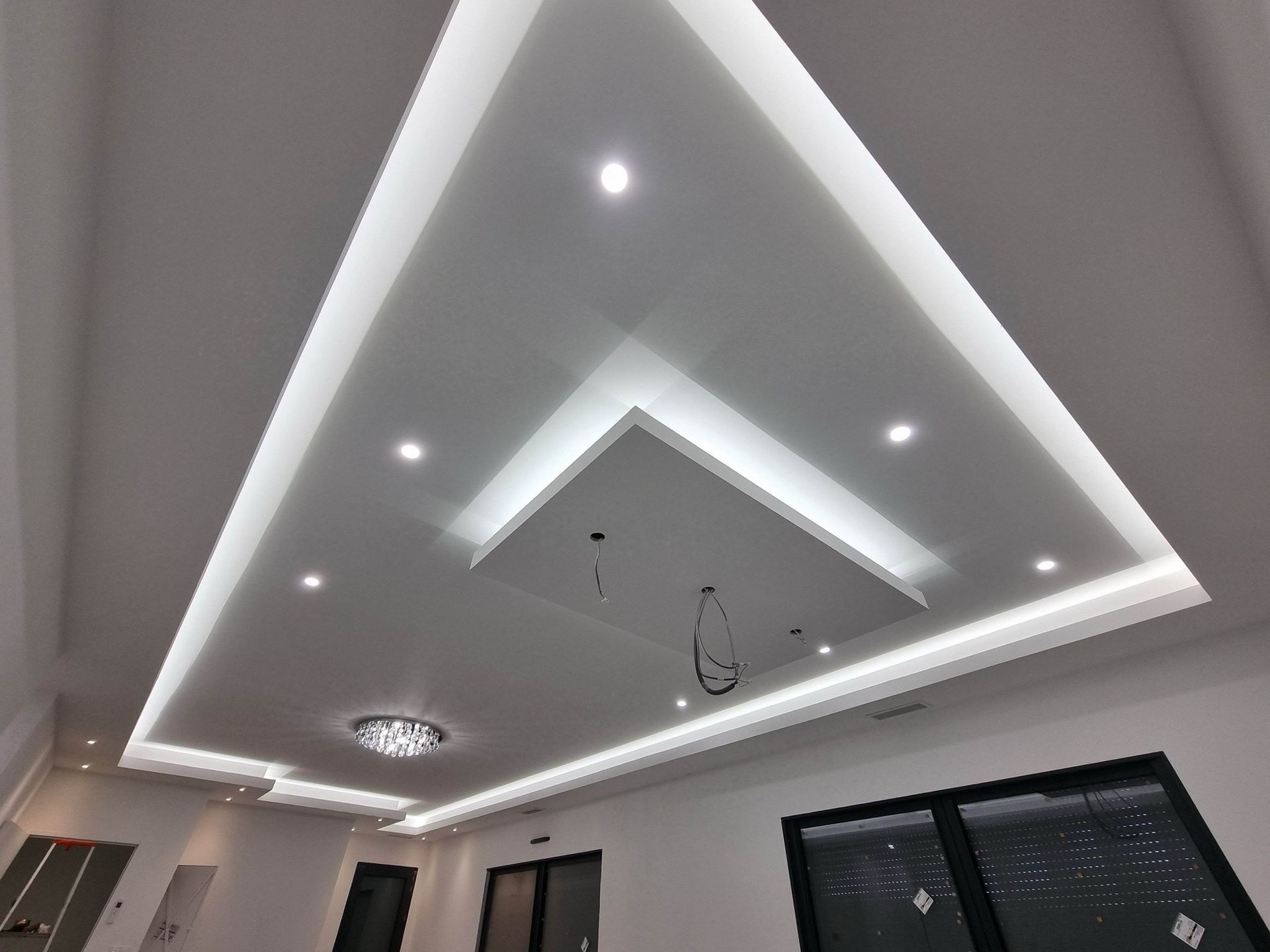 Plafond moderne avec éclairage LED encastré et spots ronds dans une pièce en construction.