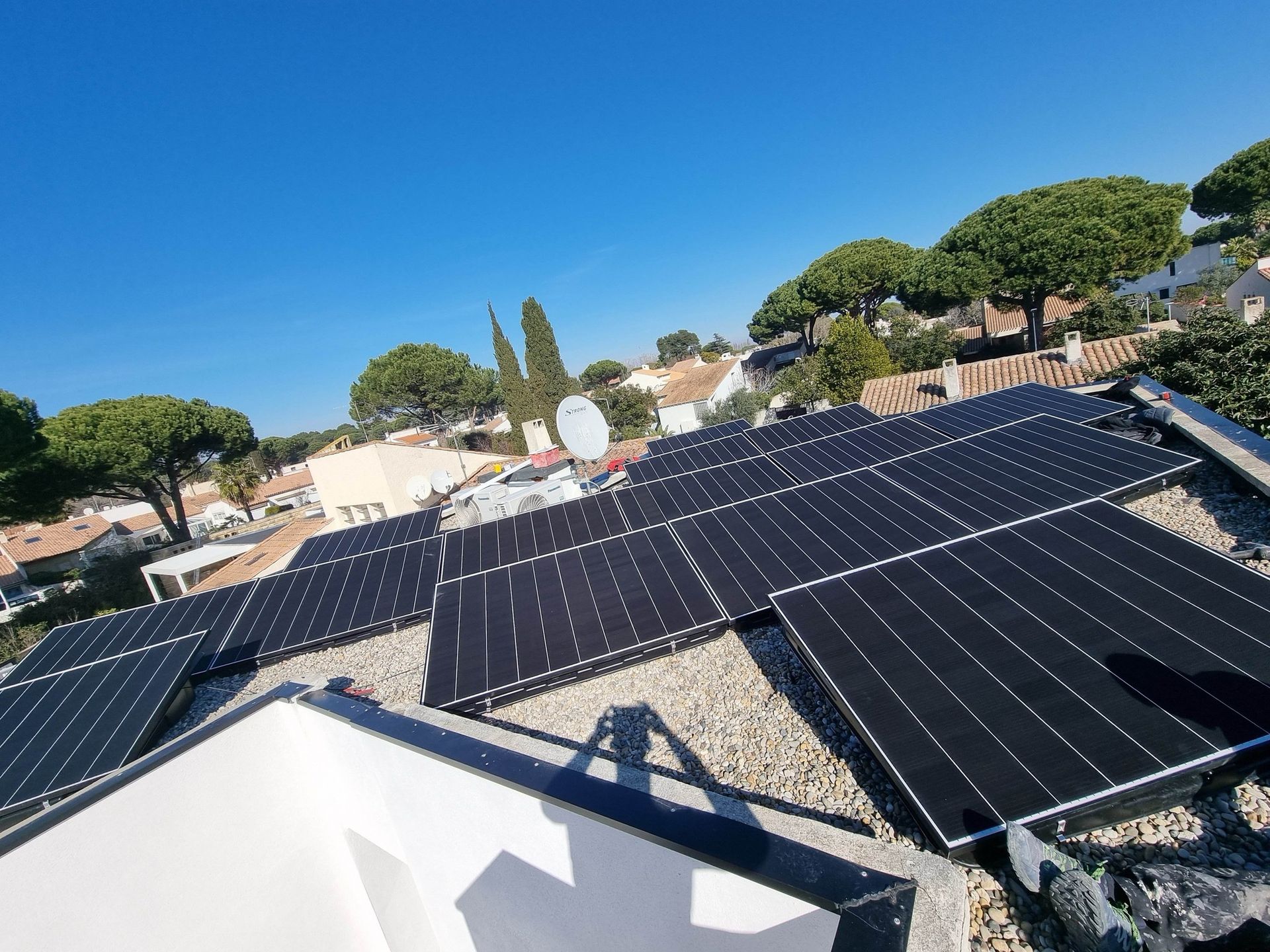 Des panneaux solaires sur un toit, avec des arbres et des maisons en arrière-plan.