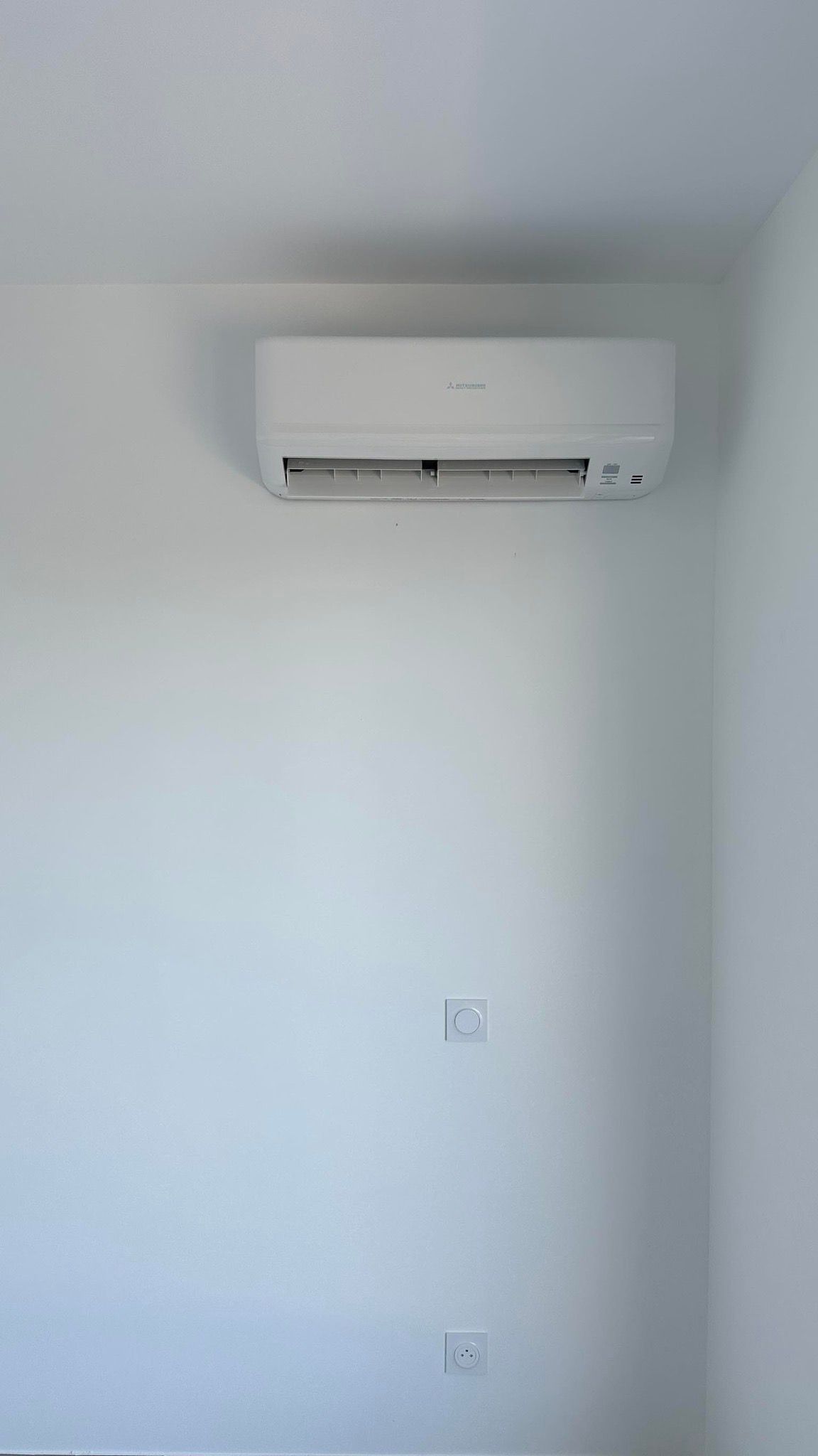 Mur avec un climatiseur mural et deux prises électriques en dessous.
