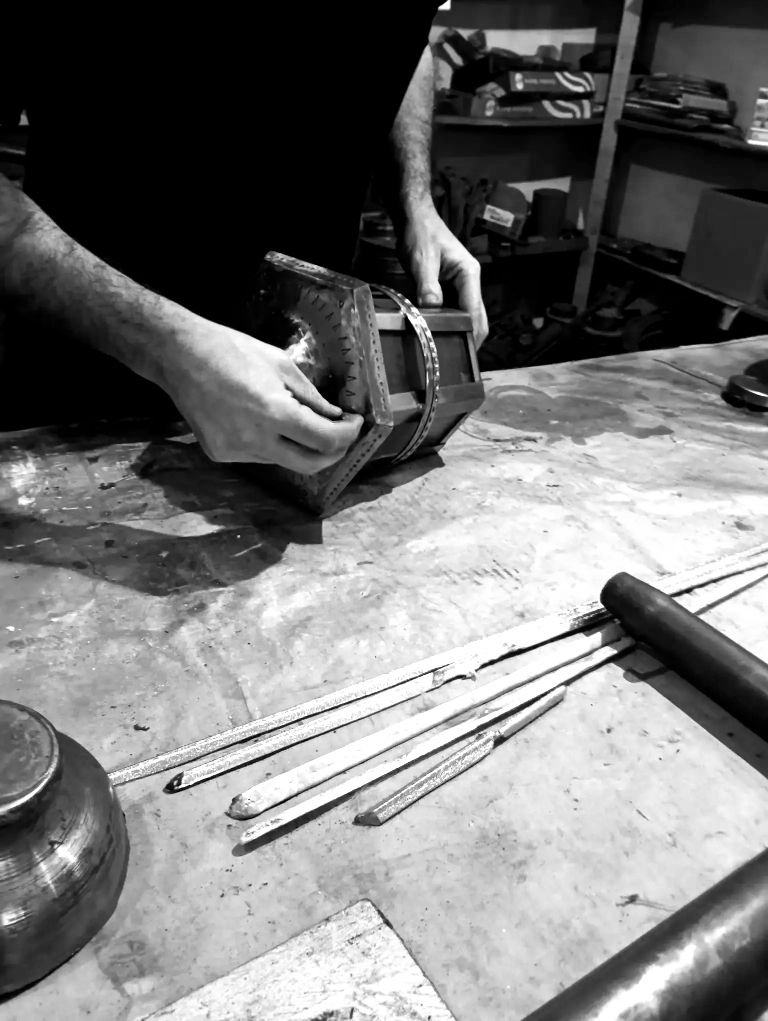 Persona ensamblando un pequeño cofre de madera en un banco de trabajo con herramientas.