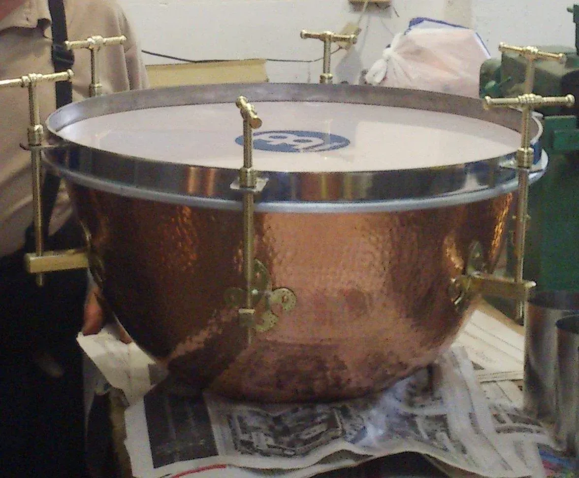 Tambor timbal de cobre con parche blanco, colocado sobre papel de periódico.