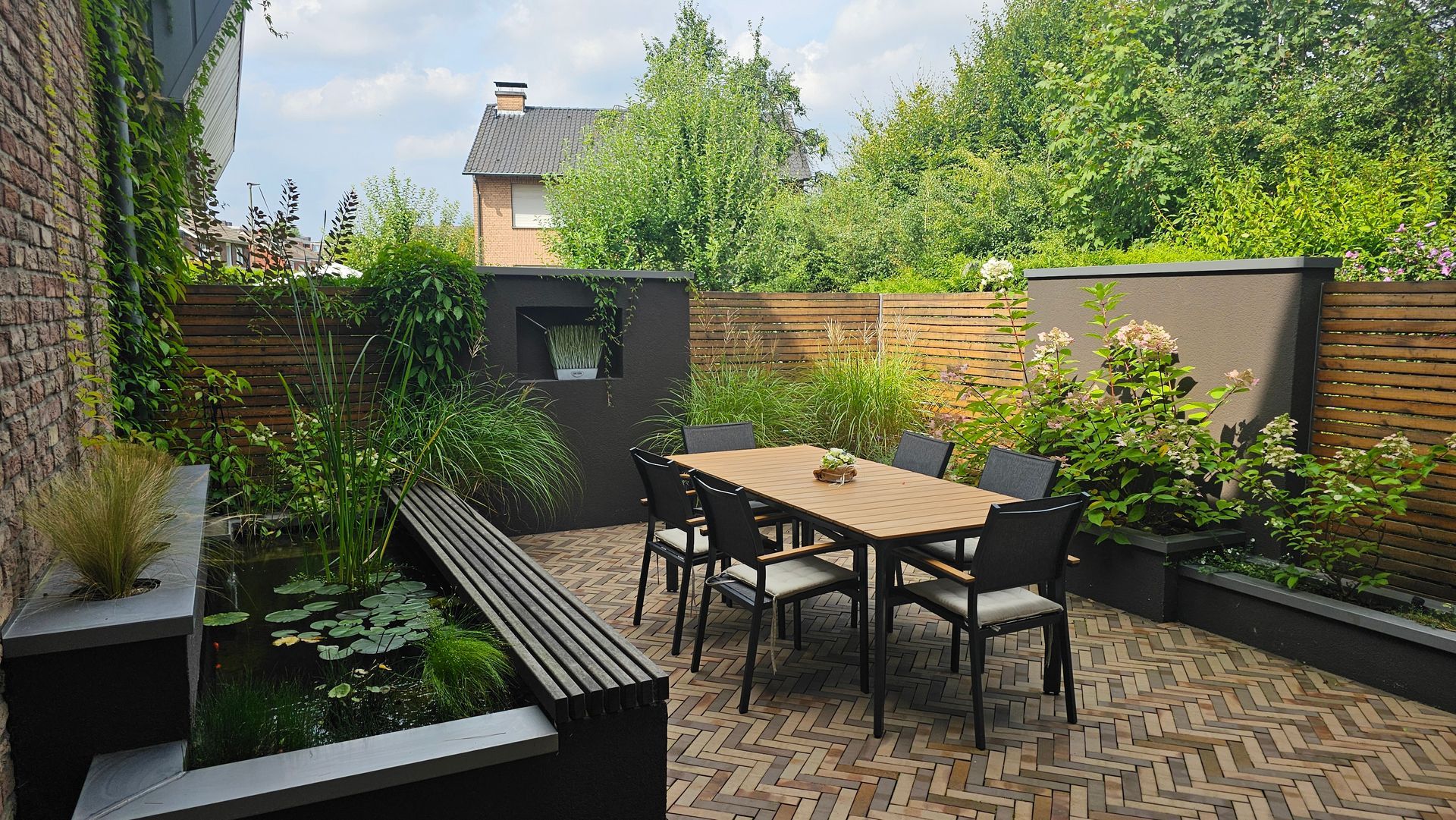 Moderner Terrassengarten mit Esstisch, Bänken, Hochbeeten und üppigem Grün in einem kleinen Innenhof