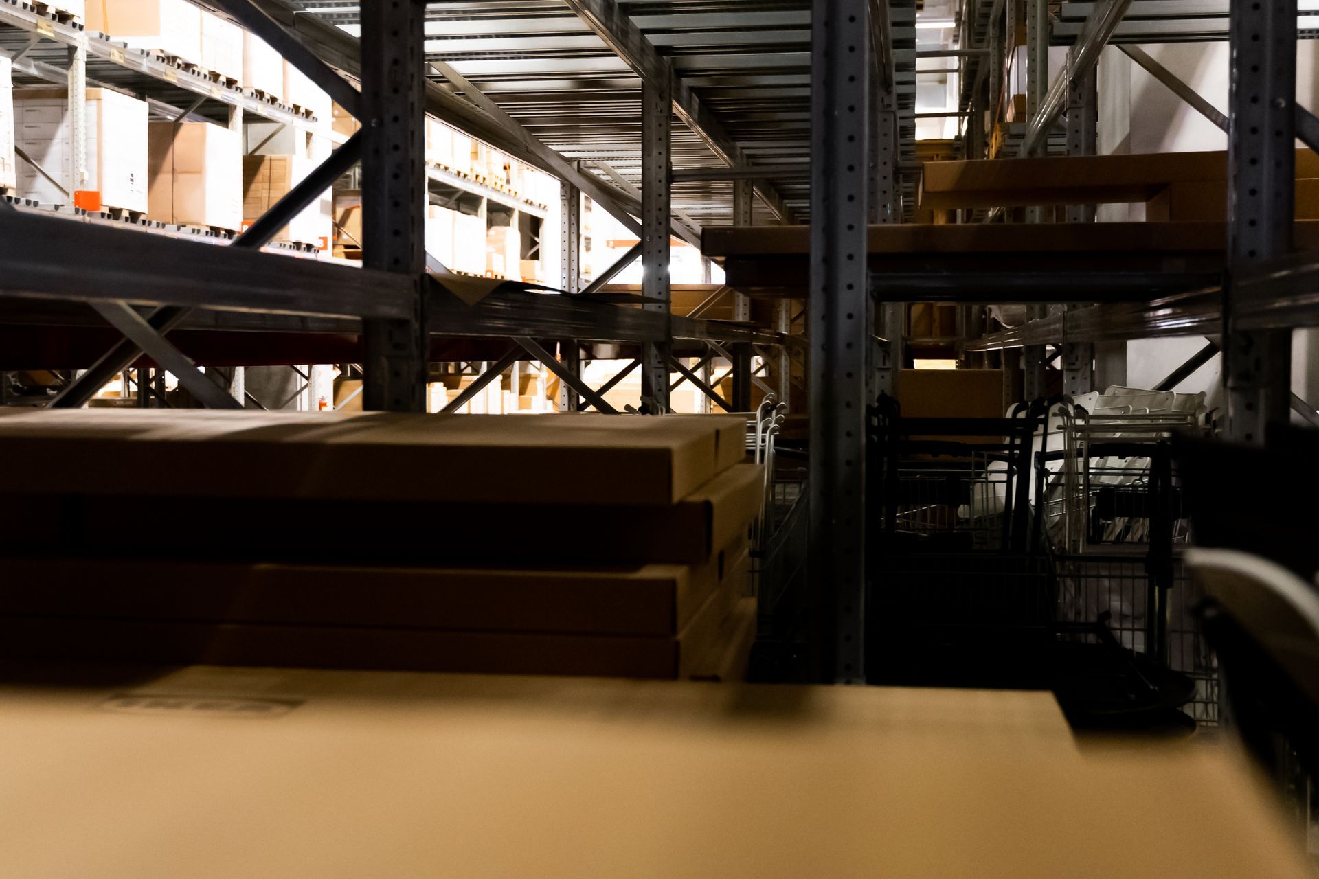 Intérieur sombre d’un entrepôt industriel avec des poutres en acier, des matériaux empilés et des machines.
