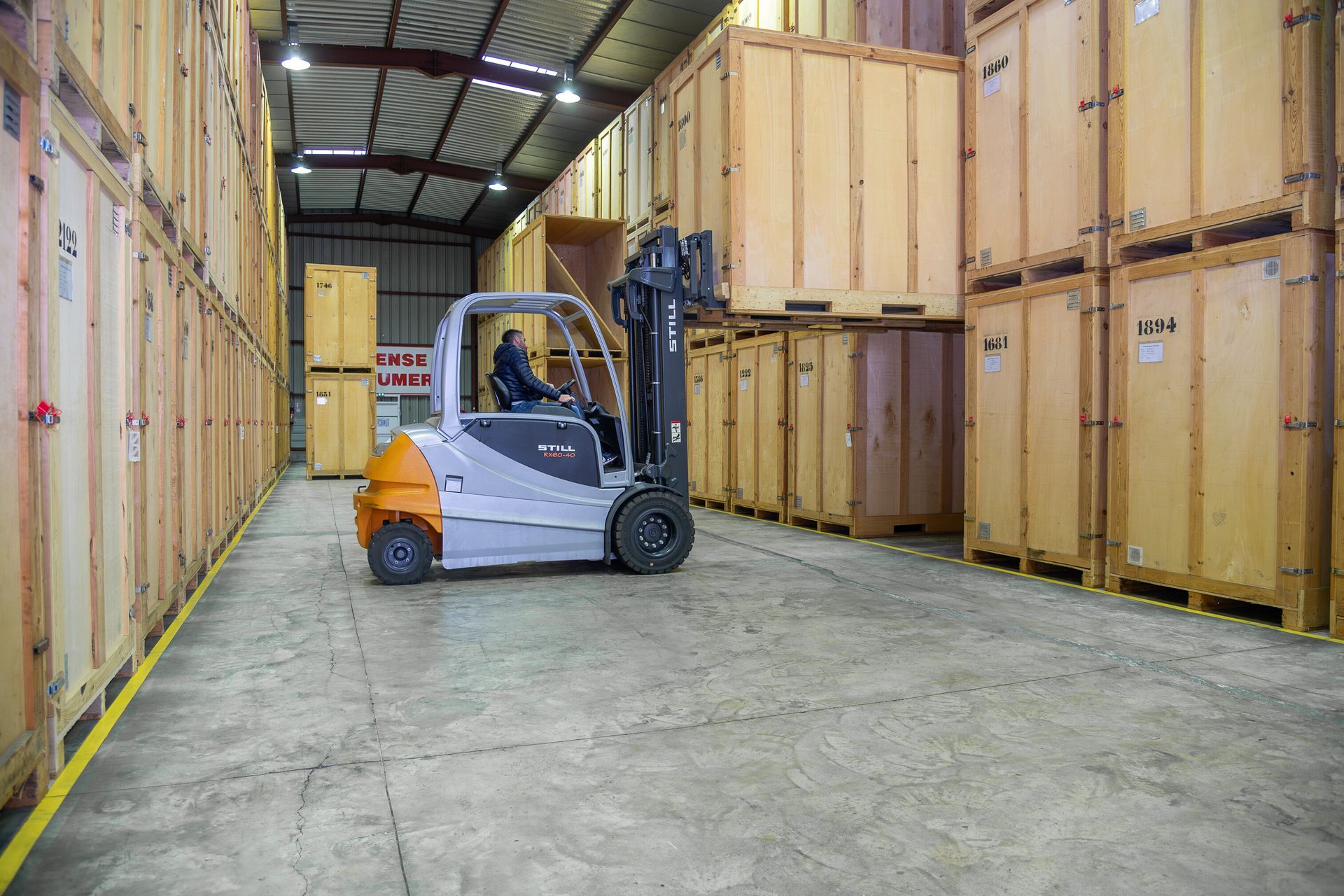 Rangée de portes rouges de box de stockage dans un garage intérieur propre, avec une ligne jaune au sol.