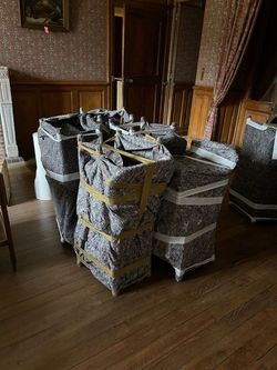 Des meubles emballés empilés sur un parquet dans une pièce faiblement éclairée