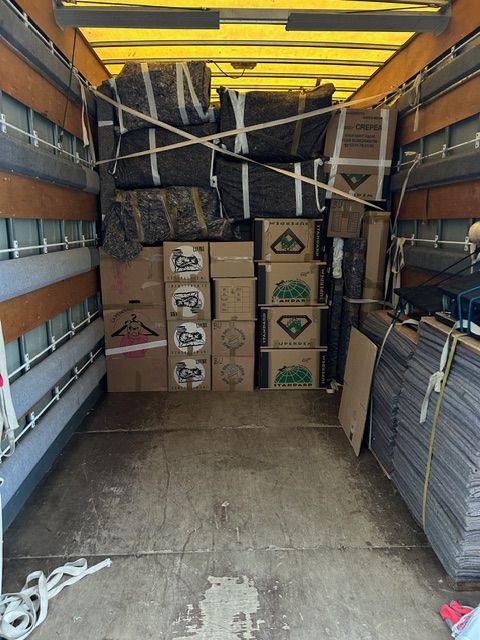 À l’intérieur d’un camion de déménagement, des cartons empilés et des objets emballés occupent l’espace de chargement.