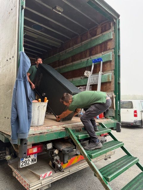 Deux personnes empilent des cartons de déménagement dans un appartement lumineux en emballant leurs affaires.