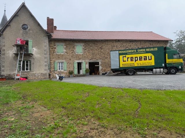 Ferme en briques à la campagne, avec un camion de déménagement jaune garé devant