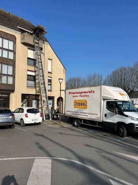 Une longue échelle à coulisse permet d’accéder à une plateforme sur le toit d’un bâtiment beige, sur fond de ciel bleu.