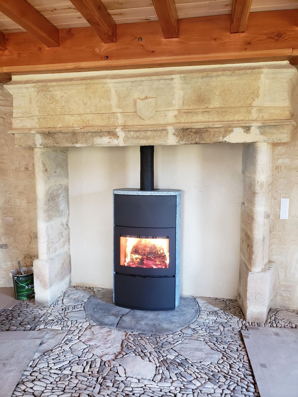 Poêle à bois rectangulaire installé dans une ancienne cheminée