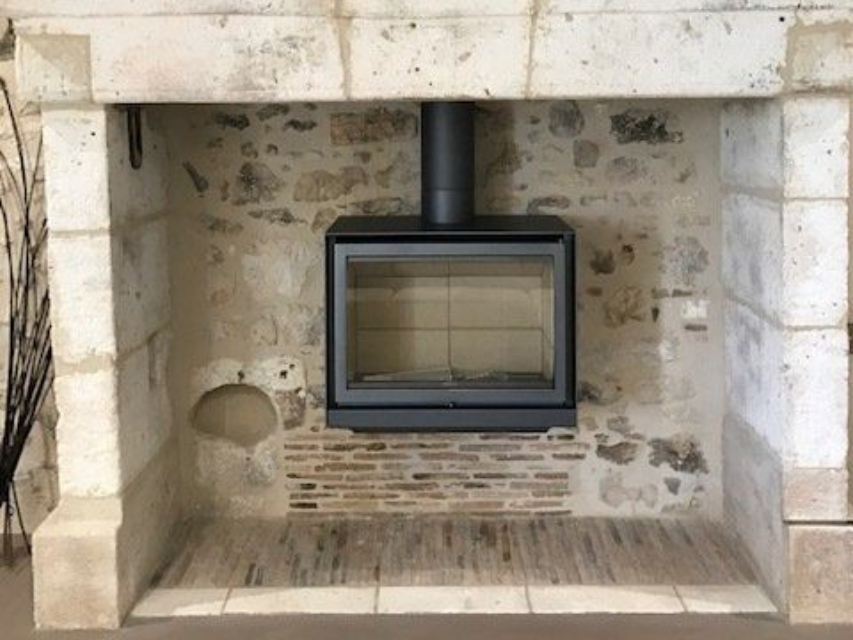 Poêle à bois rectangulaire installé dans une ancienne cheminée